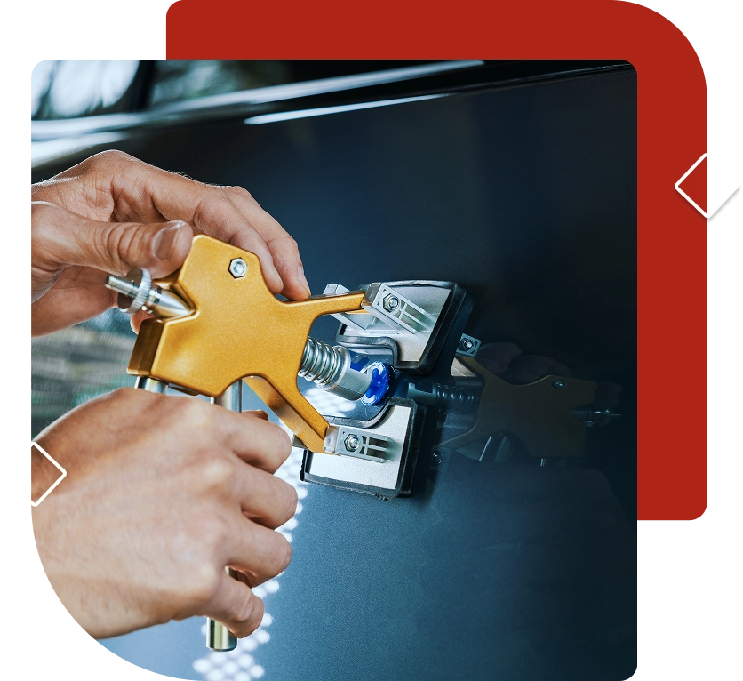 Hands using a dent puller tool on a car's dark blue body panel.