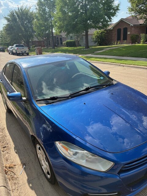 damaged car A blue car is parked on the side of the road.